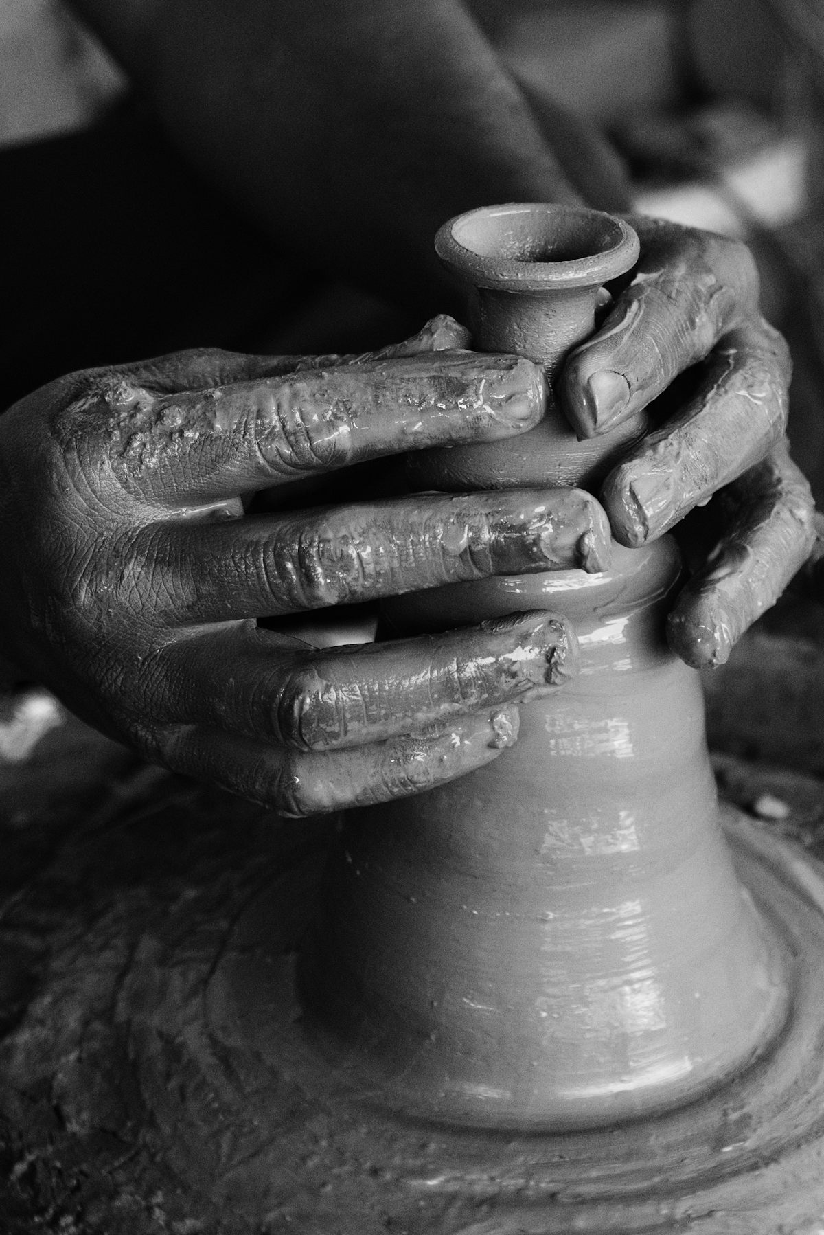 A potter's hands shaping wet clay on a turning wheel.