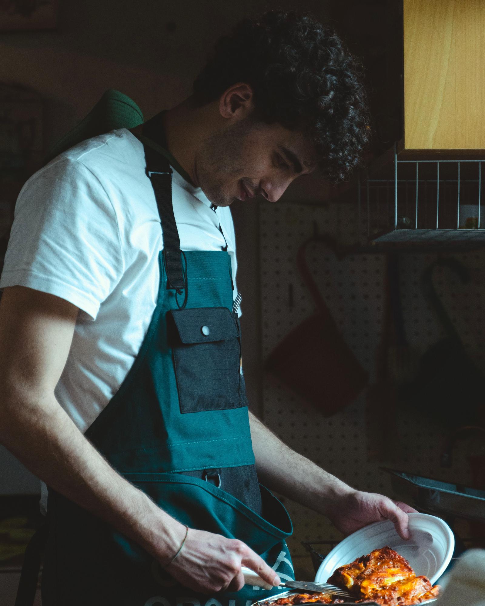 Chef preparing food in an intimate kitchen, plating a dish with focused concentration.