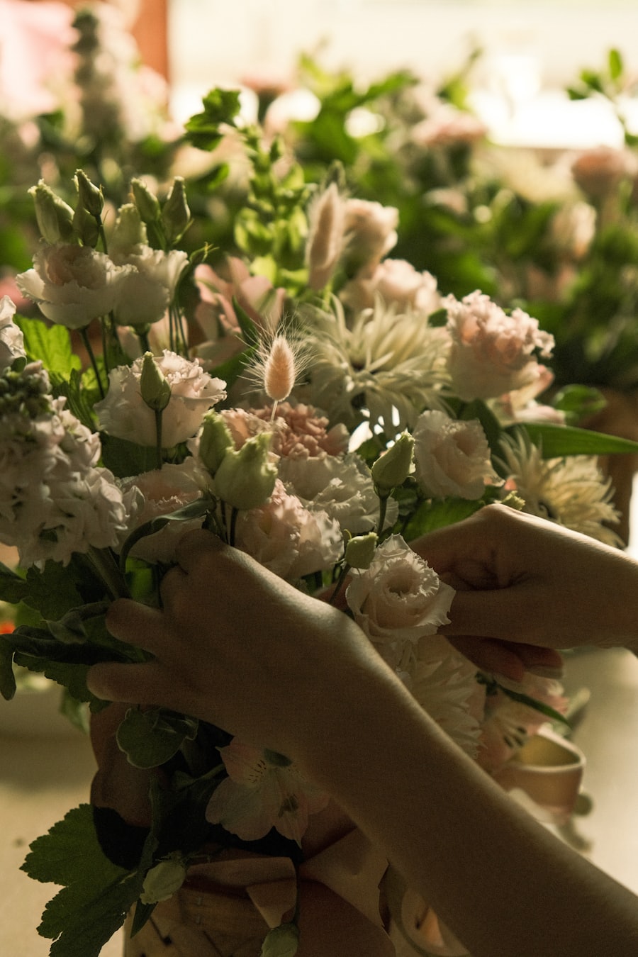 Hands arranging pale garden roses into a loose bouquet.
